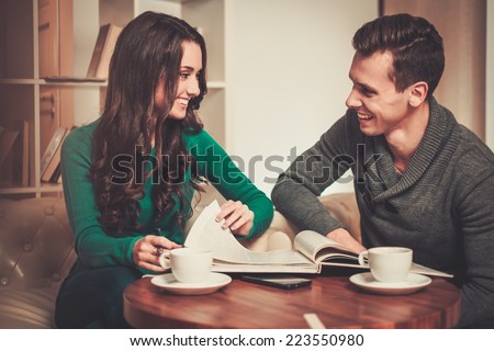 Couple with coffee and book discussing something in cafe