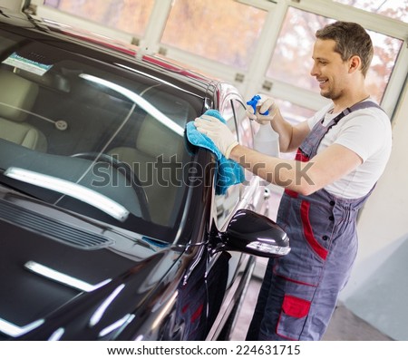 Worker on a car wash cleaning car with a spray