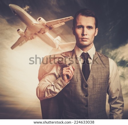 Well-dressed traveling businessman against plane in the sky