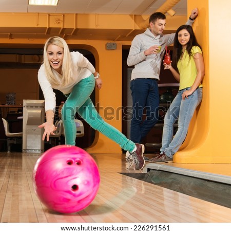 Blond smiling girl throwing ball in a bowling club