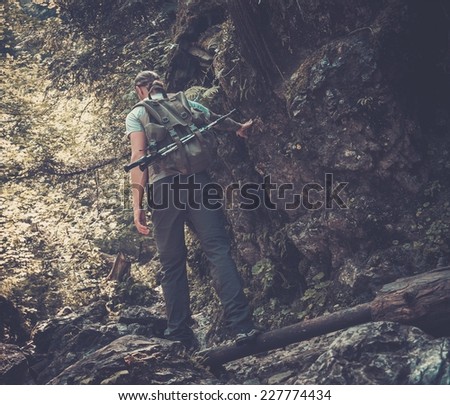 Man hiker walking across stream in mountain forest