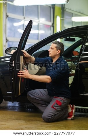 Worker on a car wash cleaning car interior