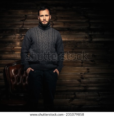 Handsome man wearing cardigan in wooden rural house interior