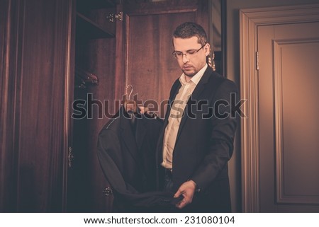 Middle-aged man taking suit from wardrobe