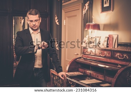 Middle-aged man looking at his wrist watch in luxury vintage style interior
