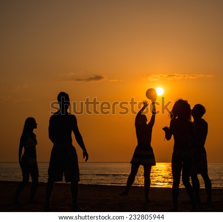 Silhouettes a young people playing with ball on a beach