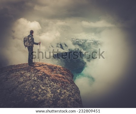 Man with hiking equipment standing on rock\'s edge