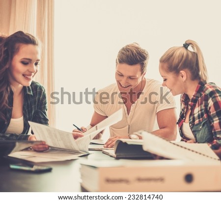 Students preparing for exams in apartment interior behind table