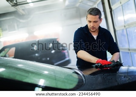Cheerful worker wiping car on a car wash