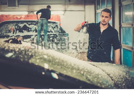 Man worker washing luxury car on a car wash