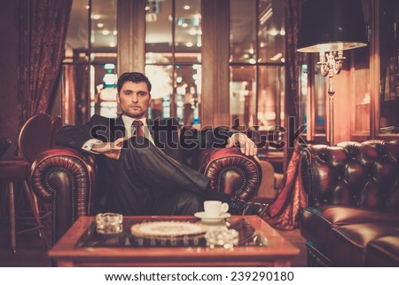 Confident handsome brunette sitting in luxury interior
