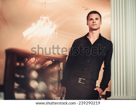Handsome young well-dressed man in luxury house interior