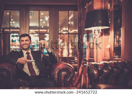 Handsome smiling man sitting with a cup of coffee in a luxury interior