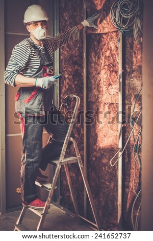 Electrician working with wires in new apartment on a ladder