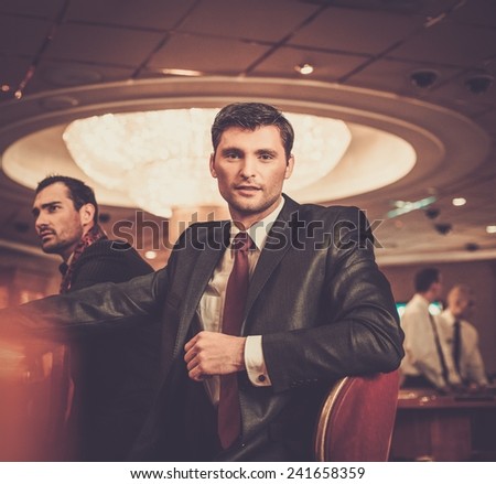 Two fashionable men in suits behind table in a casino Two fashionable men in suits behind table in a casino