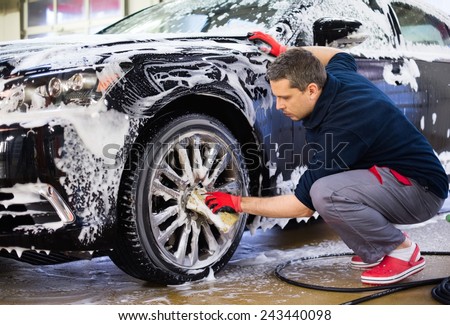 Man worker washing car\'s alloy wheels on a car wash
