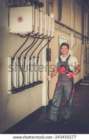 Cheerful serviceman holding hose with unbottled motor oil in a car workshop