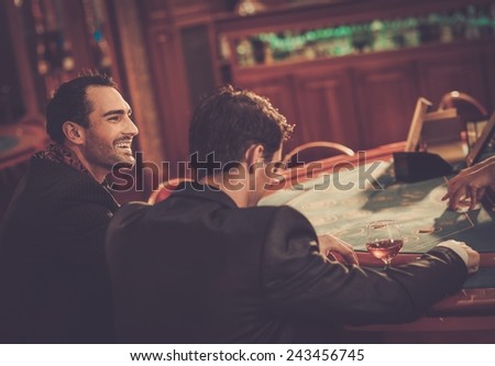 Two fashionable men in suits behind table in a casino