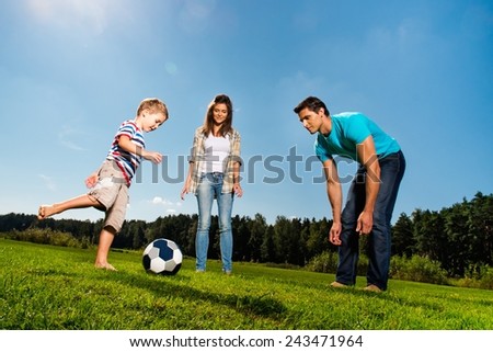 Happy young family playing football outdoors