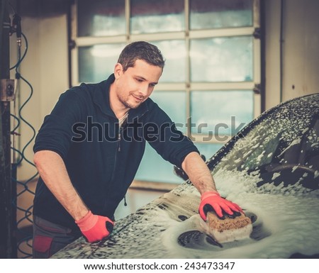 Man worker washing luxury car with sponge on a car wash