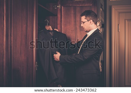 Middle-aged man taking suit from wardrobe