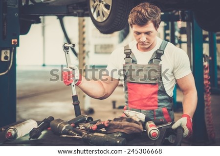 Young mechanic with tools in a car workshop