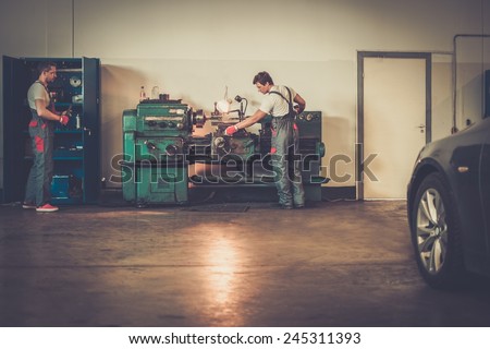 Serviceman working on turning lathe in car workshop