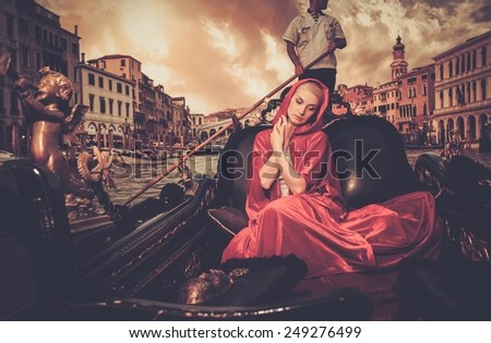 Beautiful woman in red cloak riding on gondola