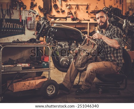 Mechanic building vintage style cafe-racer motorcycle  in custom garage