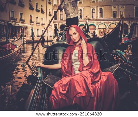 Beautiful woman in red cloak riding on gondola