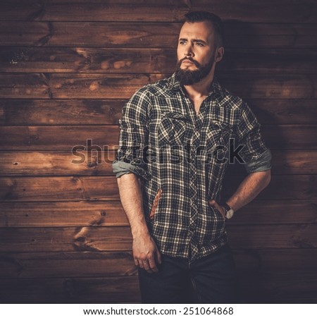 Handsome man wearing checkered  shirt in wooden rural house interior