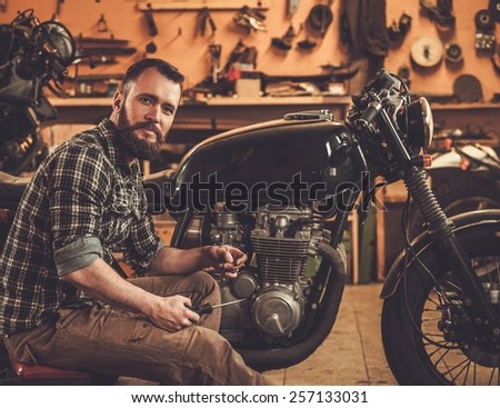 Mechanic building vintage style cafe-racer motorcycle  in custom garage