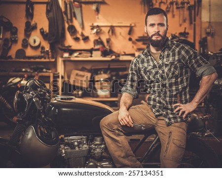 Rider and his vintage style cafe-racer motorcycle in customs garage