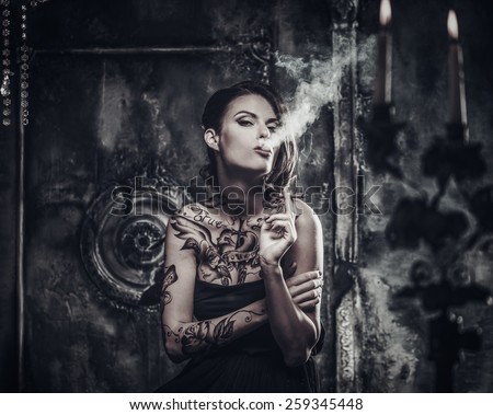 Smoking tattooed beautiful woman  in old spooky interior