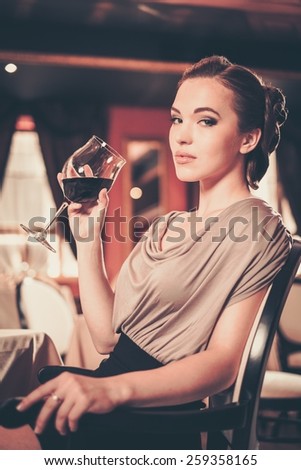 Young woman with glass of red wine alone in a restaurant