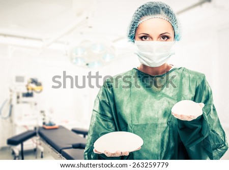 Plastic surgeon woman holding different size silicon breast implants in surgery room interior
