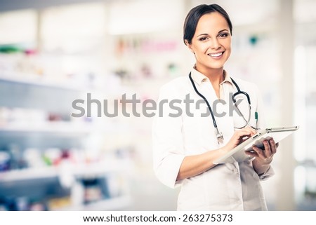 Positive brunette doctor woman in drug store with tablet pc