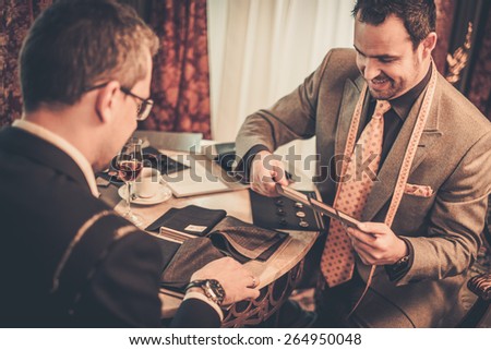 Tailor and client choosing cloth and buttons for custom made suit