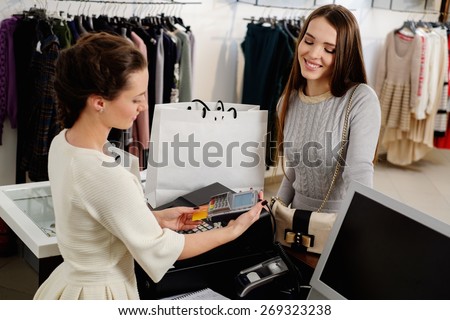 Happy woman customer paying with credit card in fashion showroom