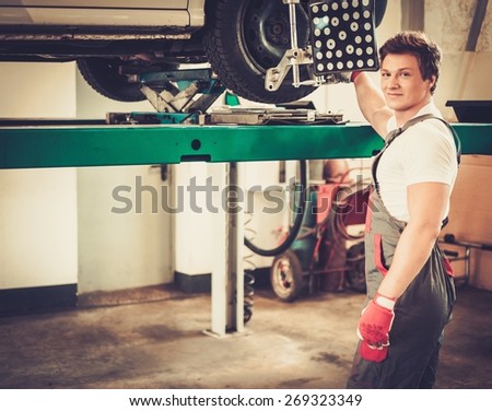 Serviceman checking wheel alignment  in a car workshop