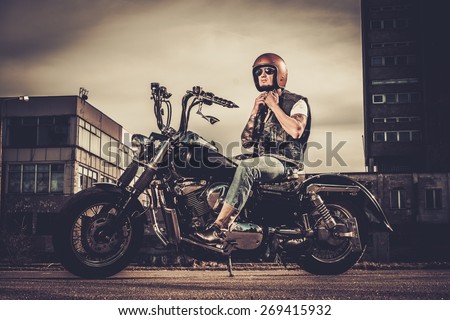 Tattooed biker and his bobber style motorcycle on a city streets