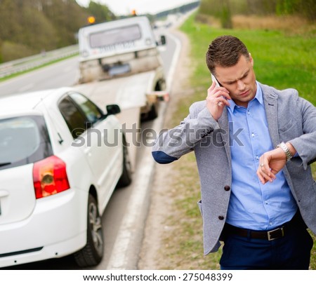 Man calling while tow truck picking up his broken car