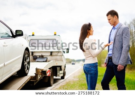 Couple near tow-truck picking up broken car