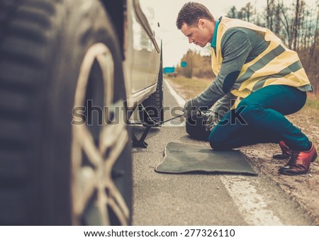 Man changing wheel on a roadside
