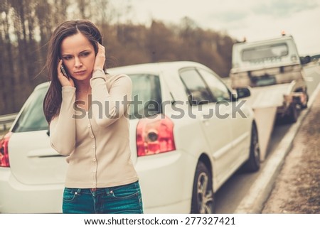 Woman calling while tow truck picking up her car