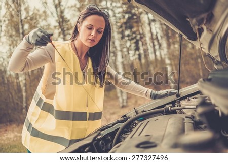 Woman checking oil level on  a roadside