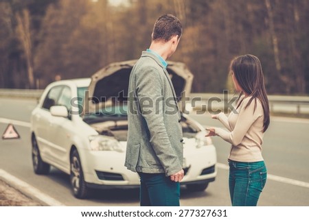 Couple near broken car on a highway roadside