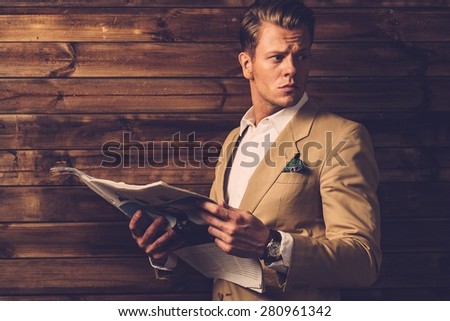 Stylish man with newspaper in rural cottage interior