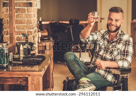 Happy client in barber shop will glass of whiskey