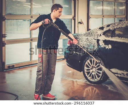 Man worker washing luxury car on a car wash